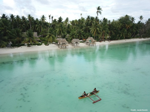 Fishers coming home on a paddle canoe after fishing on the fore reefs of Abaiang, Kiribati